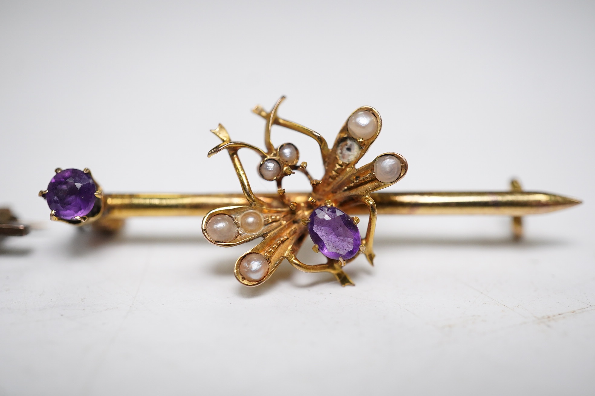 An Edwardian 375, amethyst and seed pearl set bug bar brooch, 39mm (lacking pin) and a yellow metal, garnet? and diamond chip set bar brooch, gross weight 4.4 grams. Condition - poor to fair